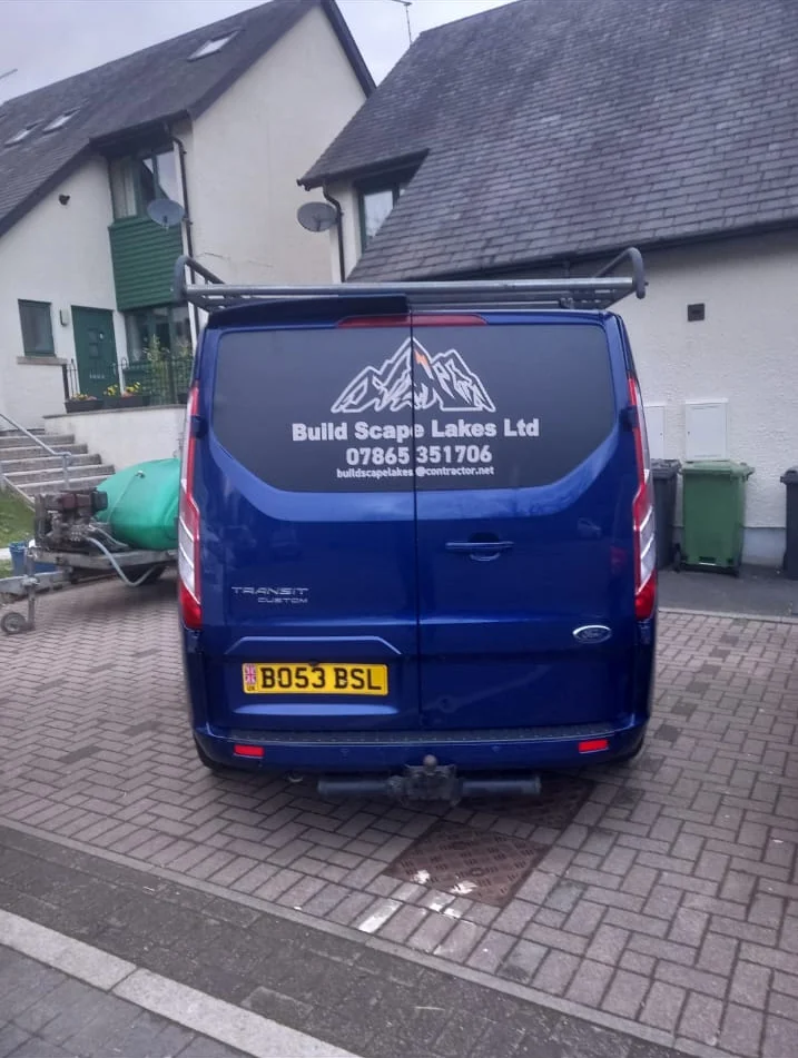 Rear of the Build Scape Lakes van showing the mountain logo and contact details, with the pressure washing trailer alongside
