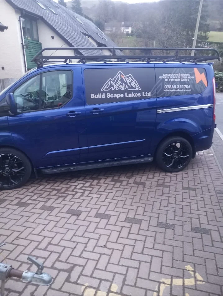 Side of Charlie's blue Build Scape Lakes van showing the company branding and services